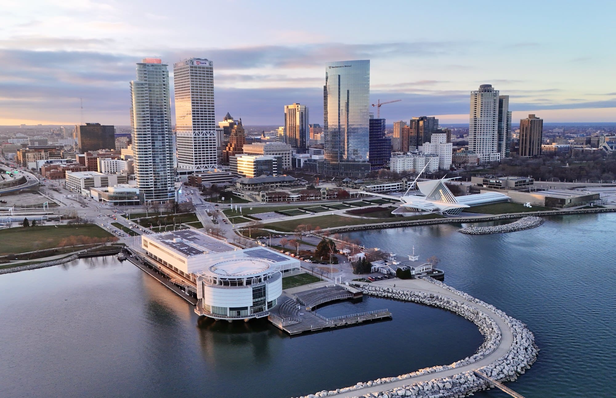 Milwaukee skyline at sunset with downtown towers, waterfront buildings, and Lake Michigan